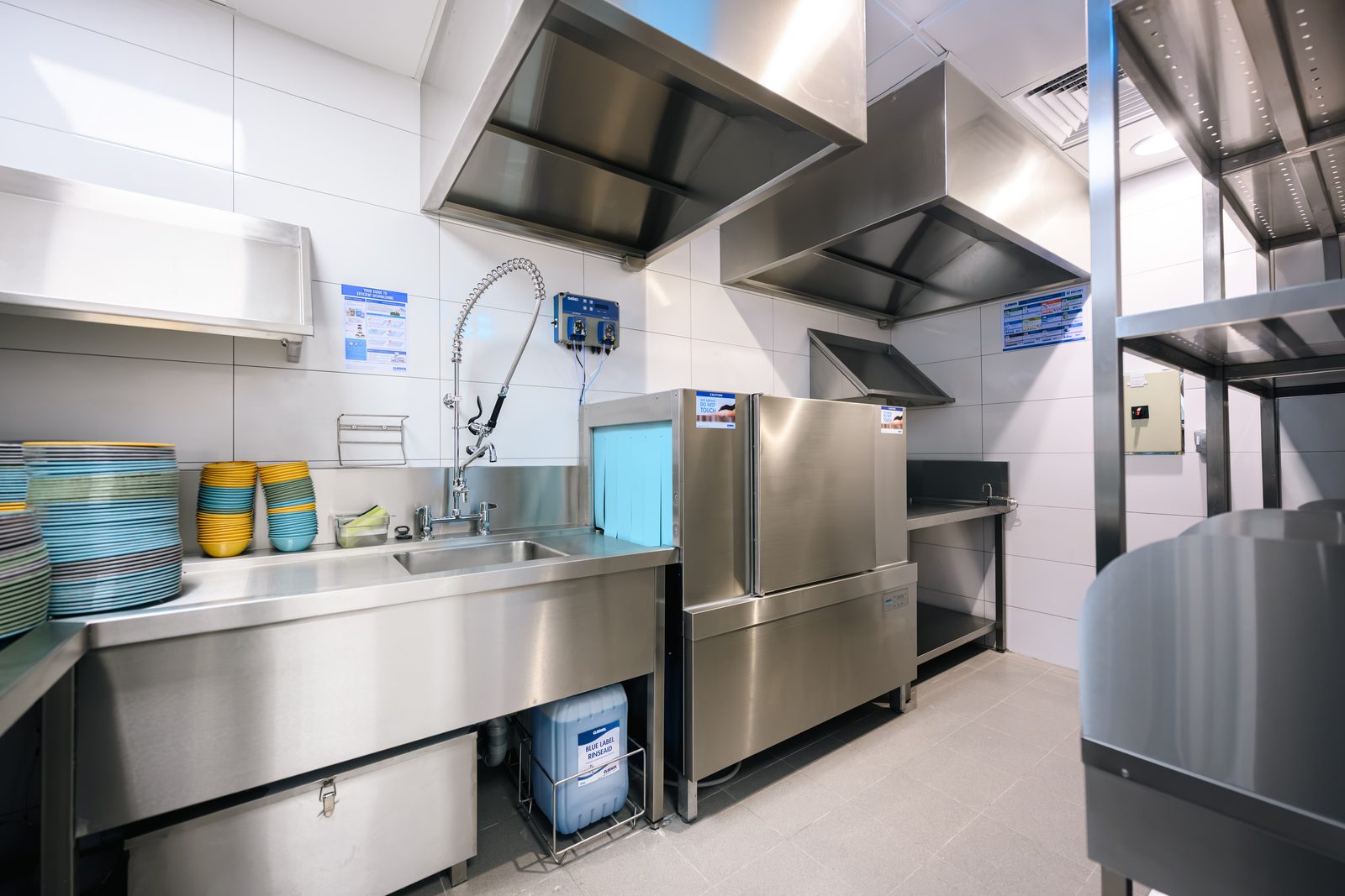 Cleresdyne-installed Winterhalter C50M rack conveyor dishwasher running left to right, with loading table and pre-rinse on the soiled side, clean tabling at the exit, extraction hood and chemical dosing