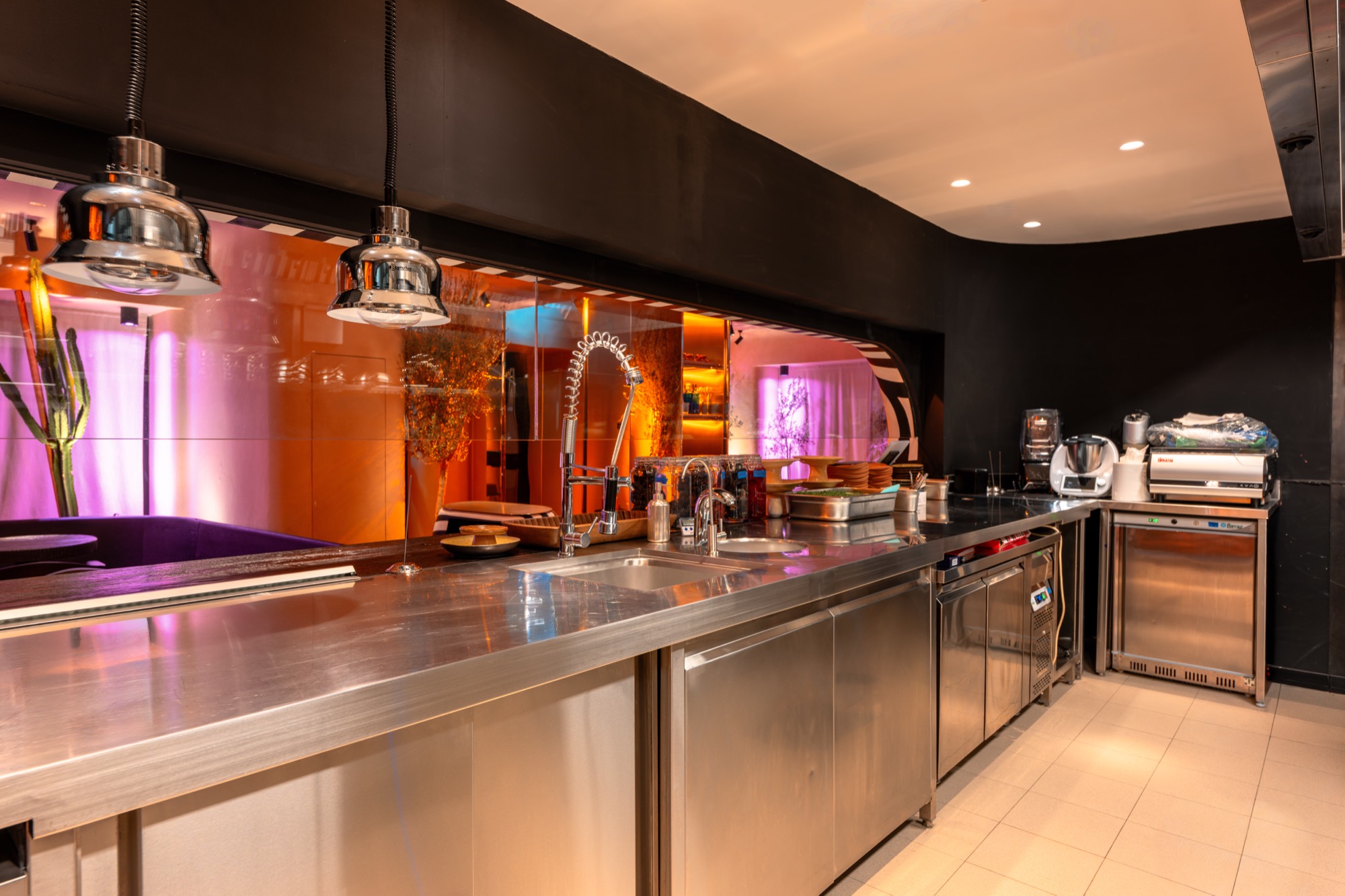 Sobremesa mirror-finish stainless steel cladding behind the back bar, catching ambient spirit shelf lighting